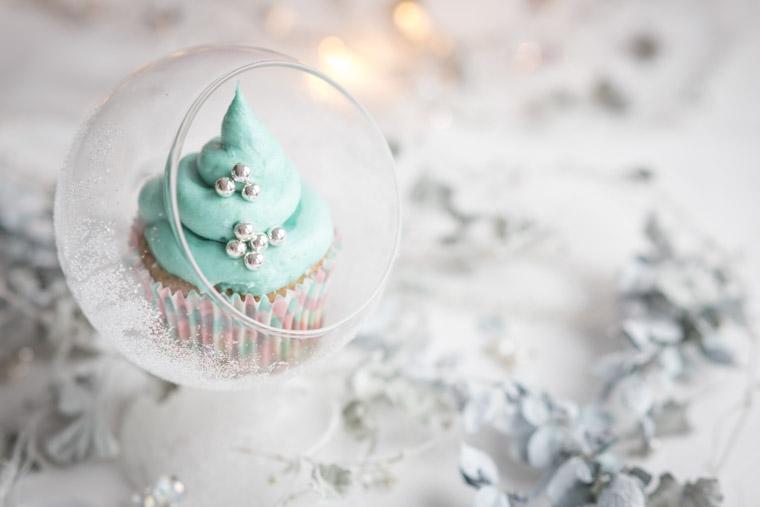 sagolik mousse spritsad på en muffins med en omgivning av blå frusna blad, av anna Winér