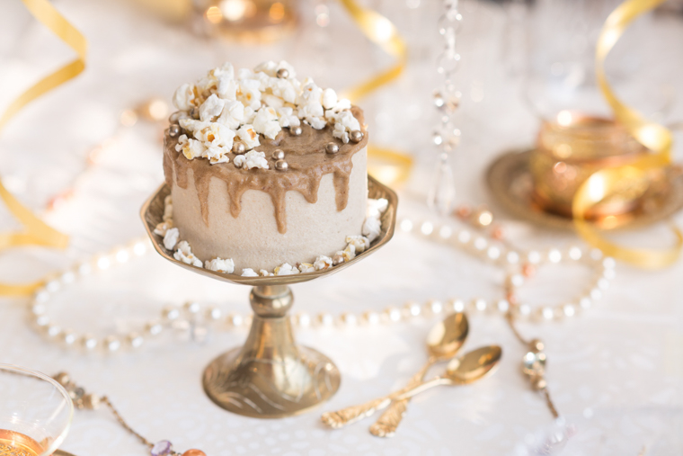 Cheesecake med kolasås & popcorn på ett guldigt fat foto av anna winér