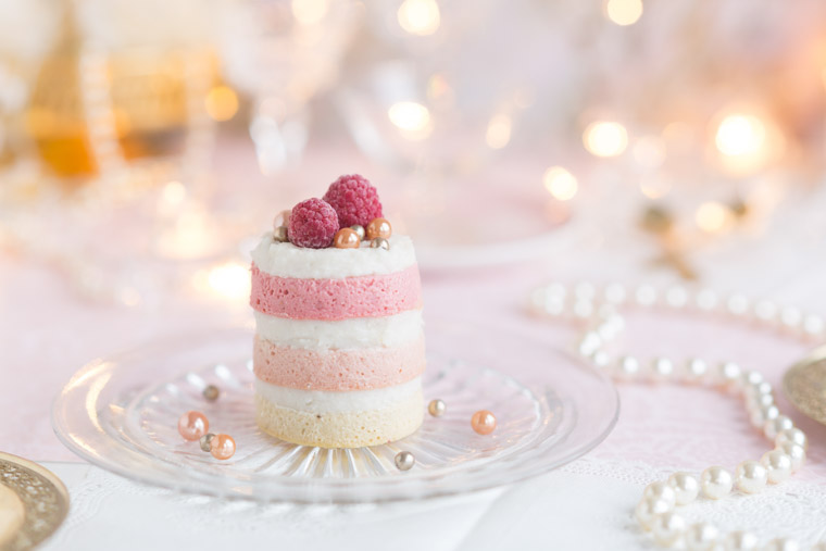 bakelse med rosa bottnar varvade med ljus kräm och bär på toppen, av Anna Winér
