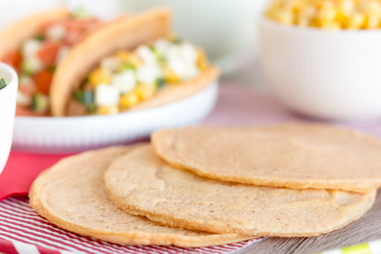 tortillabröd som ligger på en servett med fyllda tacos i bakgrunden, av Anna Winér